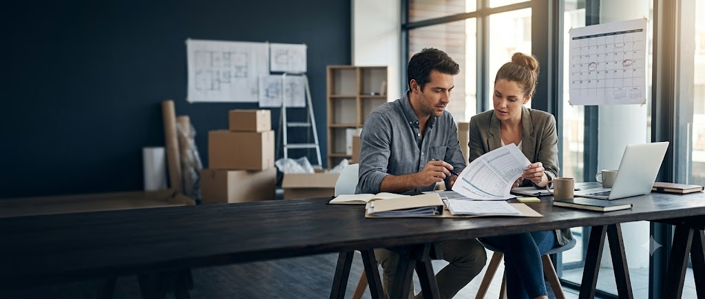 Founders reviewing a pre-opening cost register while a new business space is being set up